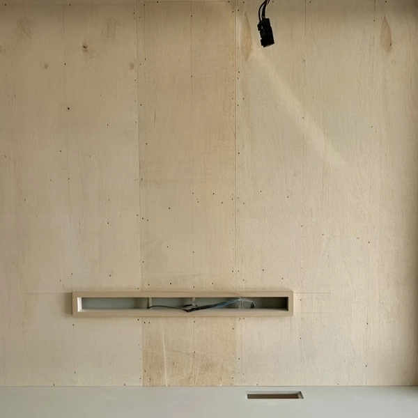 unfinished plywood wall with an rectangular cutout for wiring
